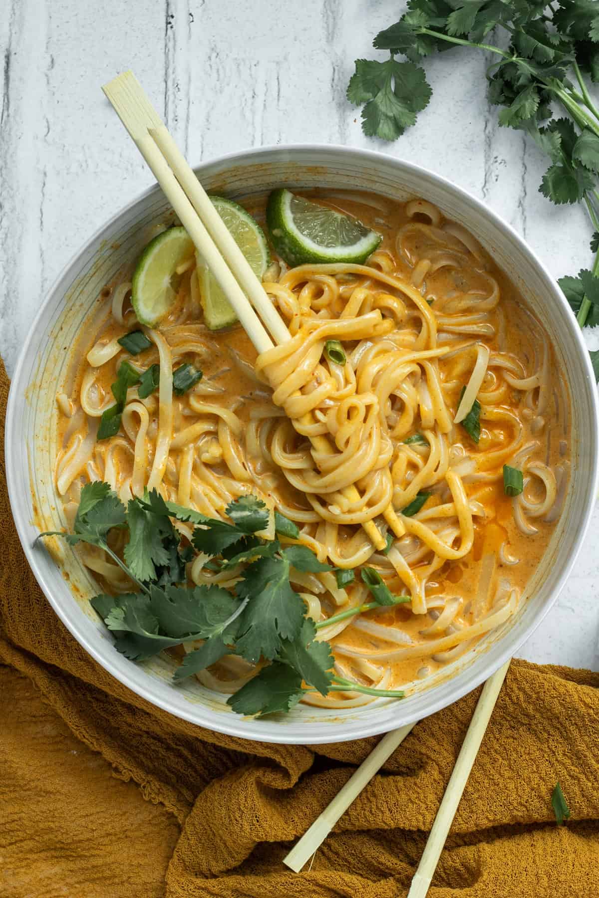 red curry noodles in a white bowl with chopsticks.